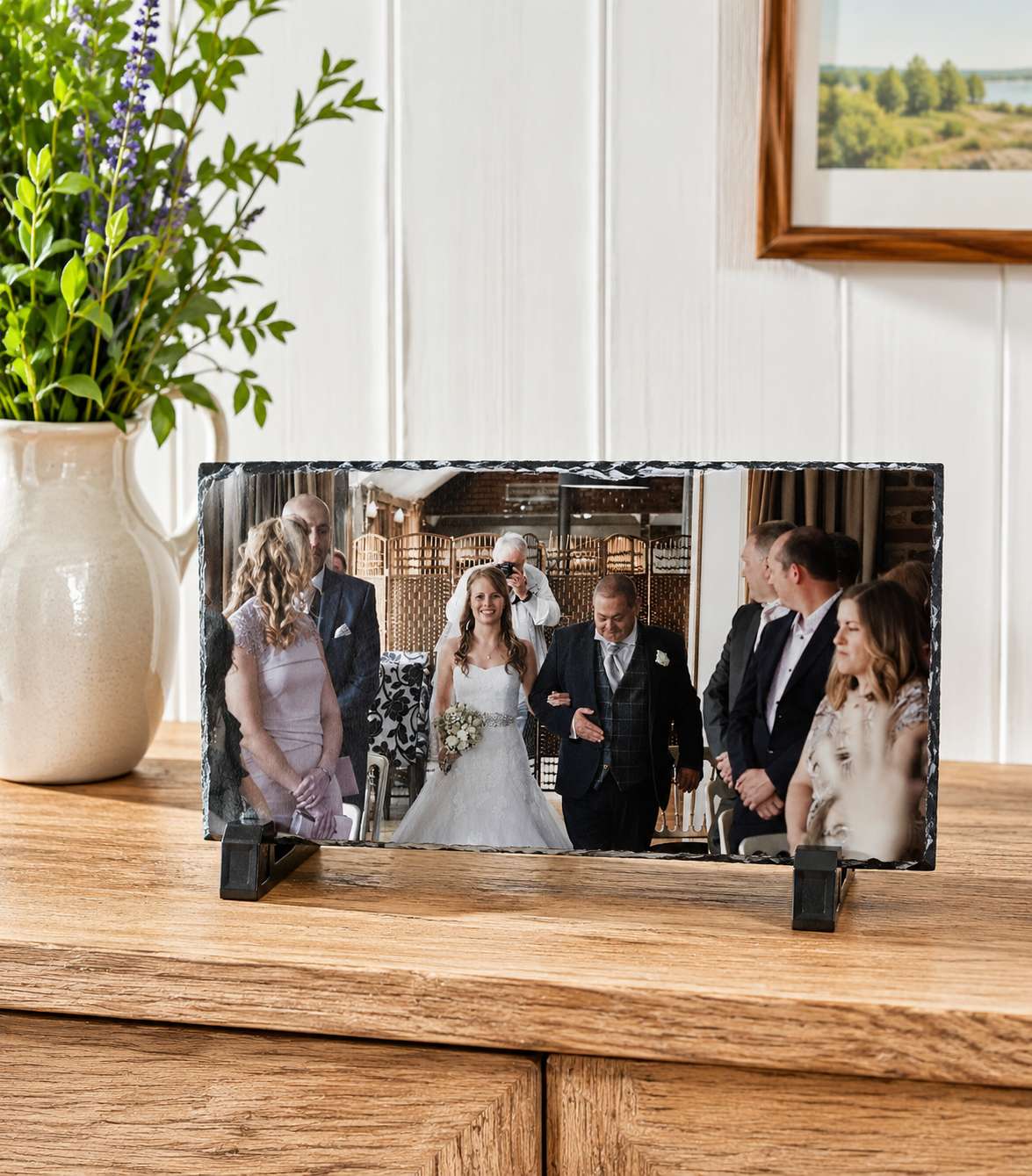 Glass photo display on a wooden surface with a wedding scene inside