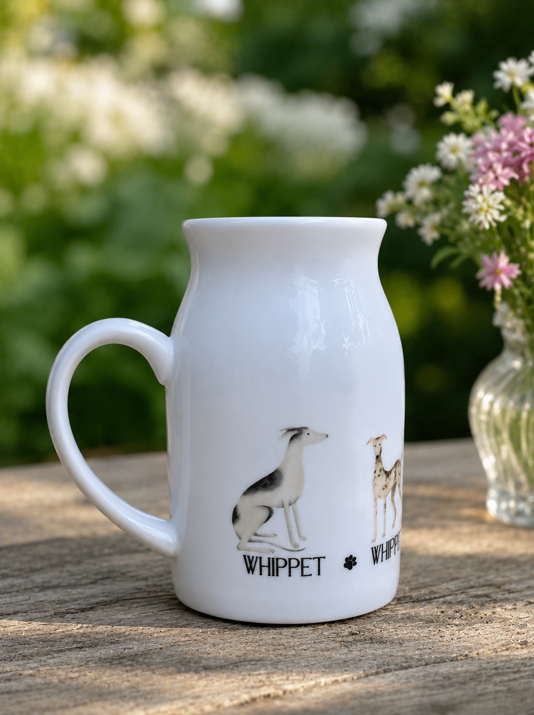 White ceramic mug with whippet illustrations on a wooden surface with flowers in the background