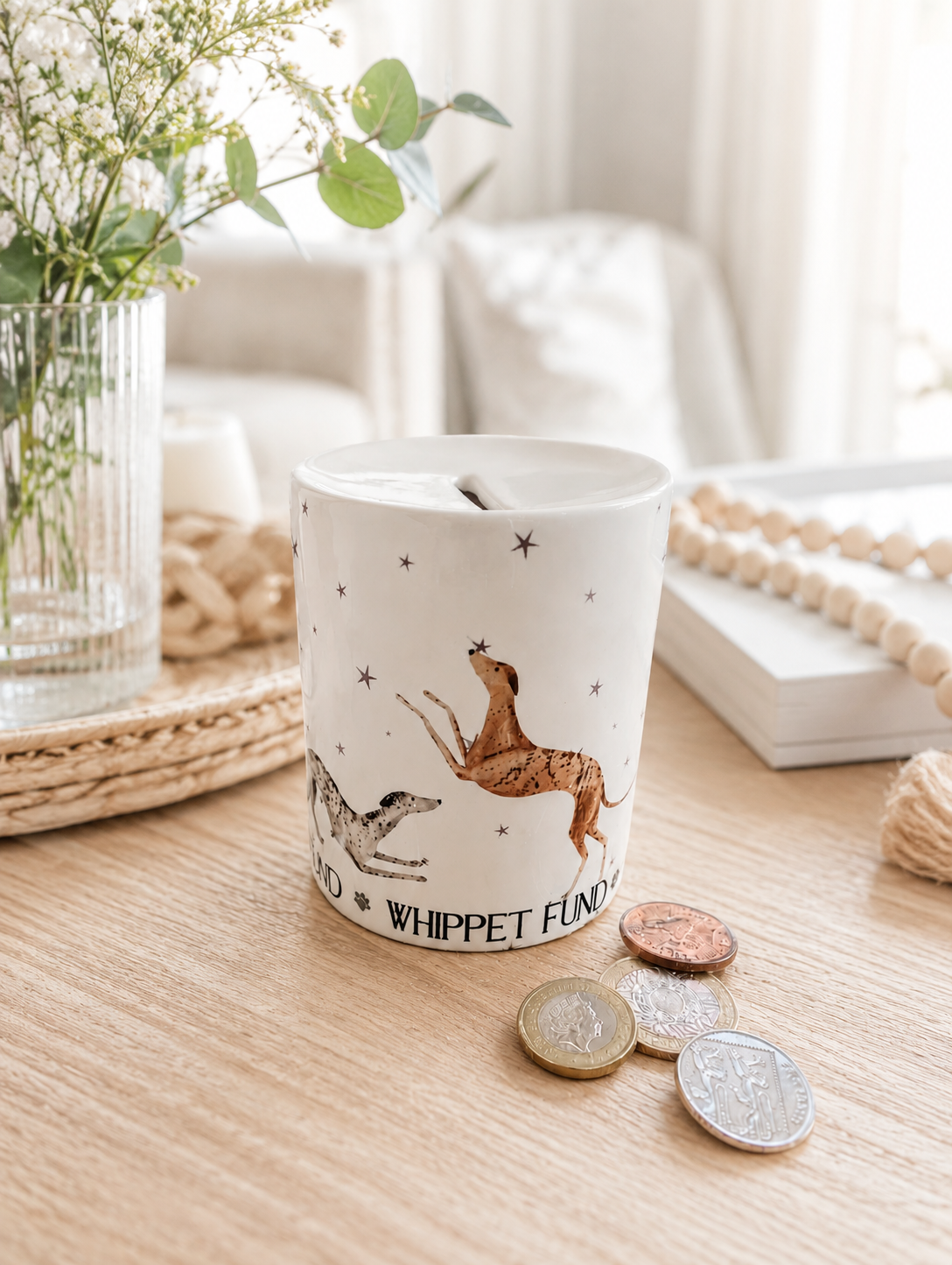 Money box with dog illustrations on a wooden surface with coins around