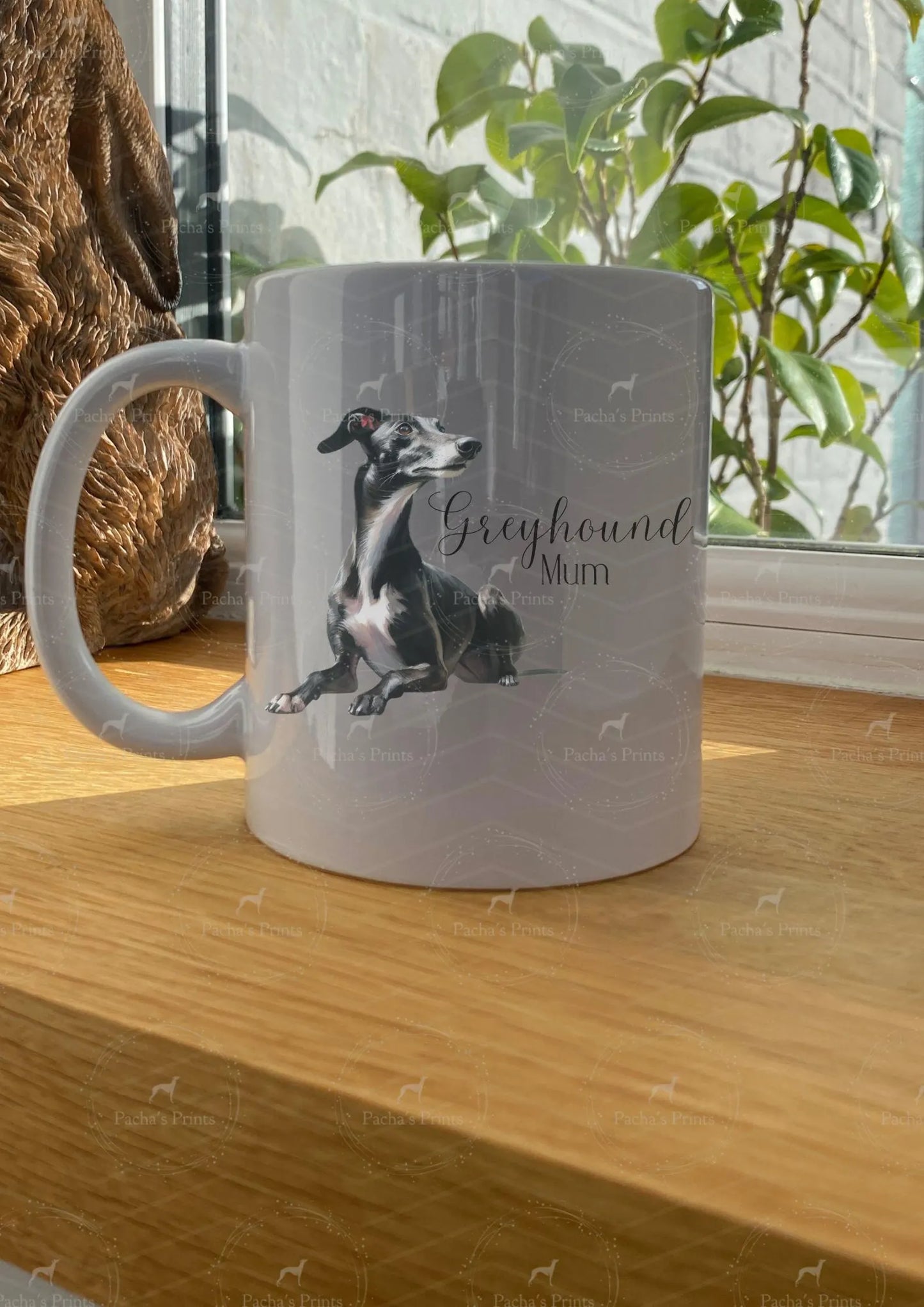 White mug with a greyhound design and text on a wooden surface.