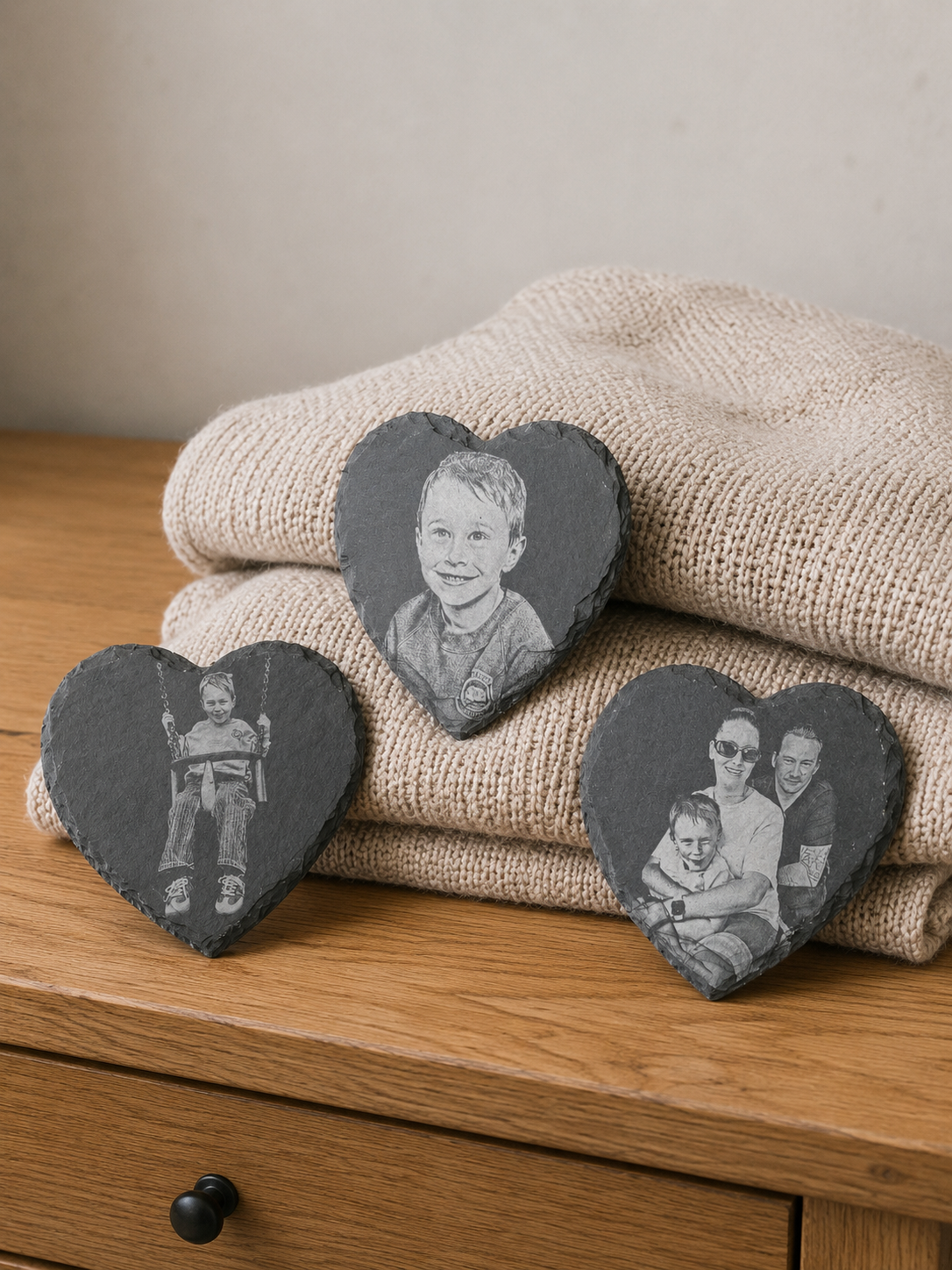 Heart-shaped slate tiles with family photos on a wooden surface with a beige blanket.