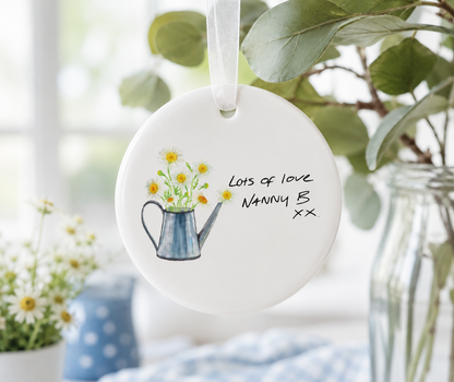 Decorative hanging plate with a teapot and flowers illustration and text, placed in a home setting.
