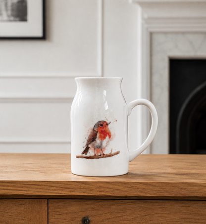 White ceramic pitcher with a robin design on a wooden surface.