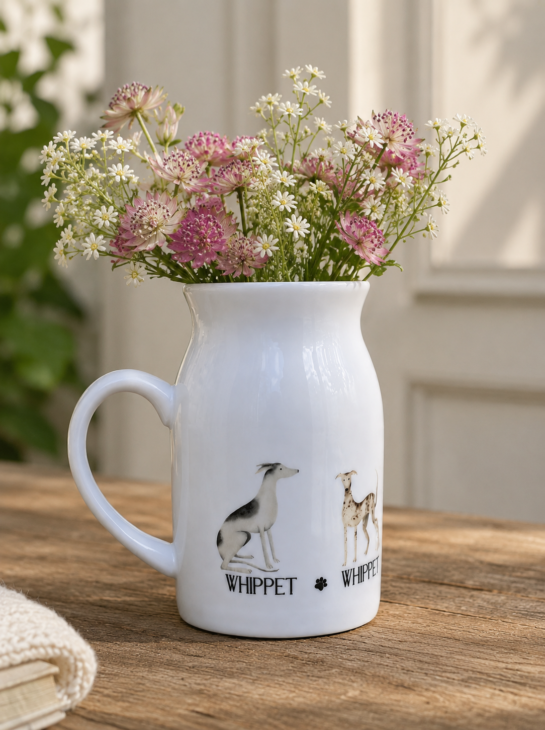 White pitcher filled with flowers on a wooden surface