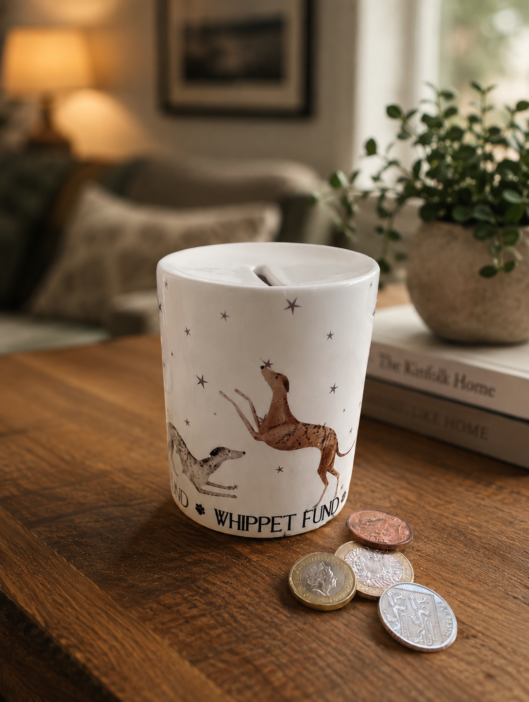 White ceramic money box with dog illustrations on a wooden surface with coins around it.
