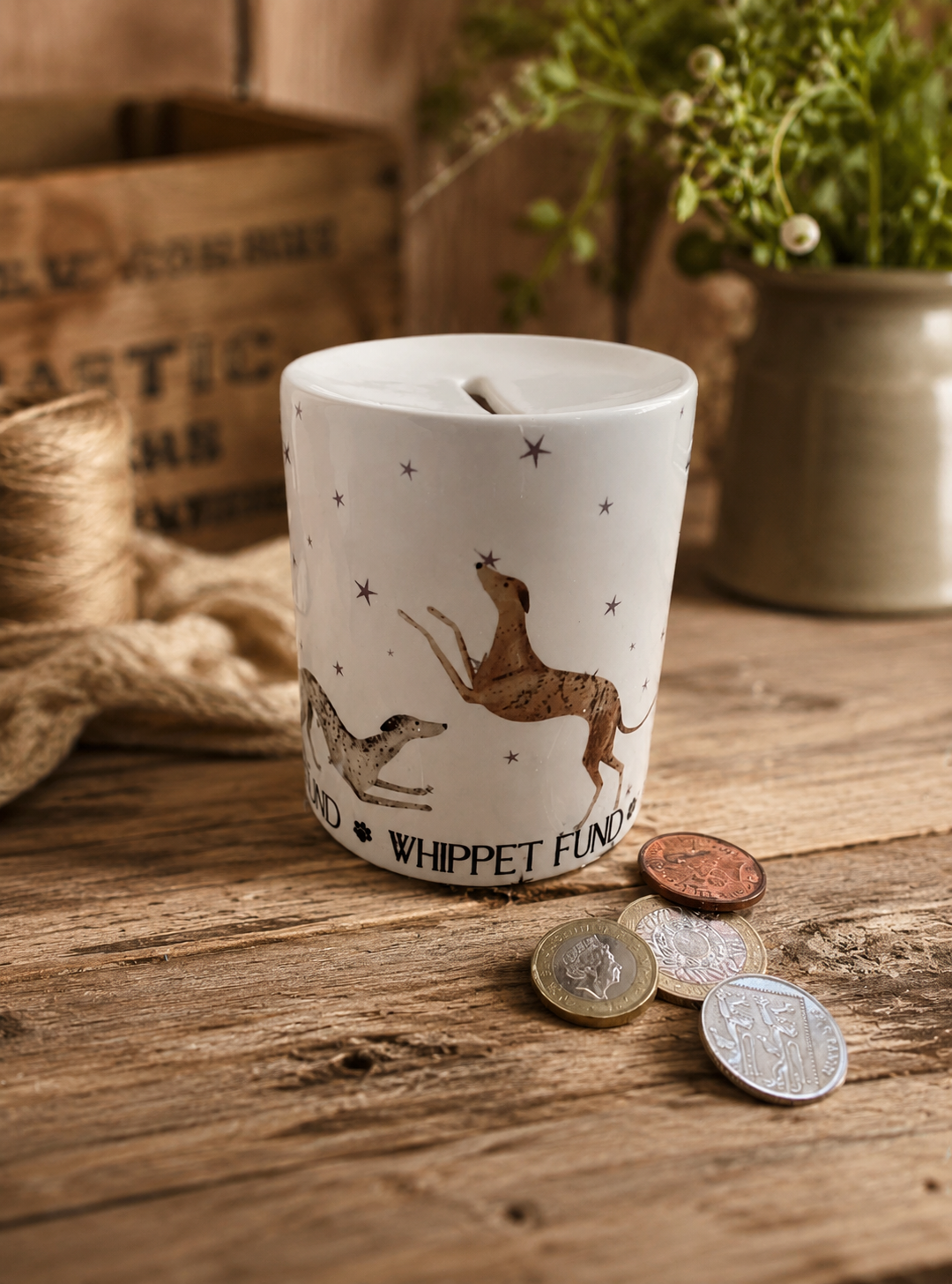 White ceramic money box with dog illustrations on a wooden surface with coins around